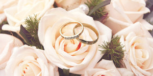 Gold diamond wedding rings on light pink roses