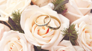 Gold diamond wedding rings on light pink roses